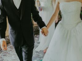woman wearing white wedding gown holding hands with man while walking